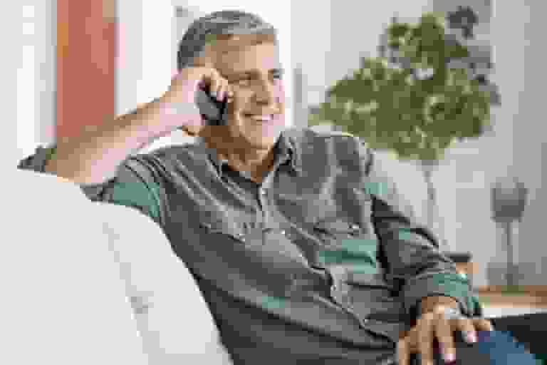 older man sitting on couch talking on cell phone