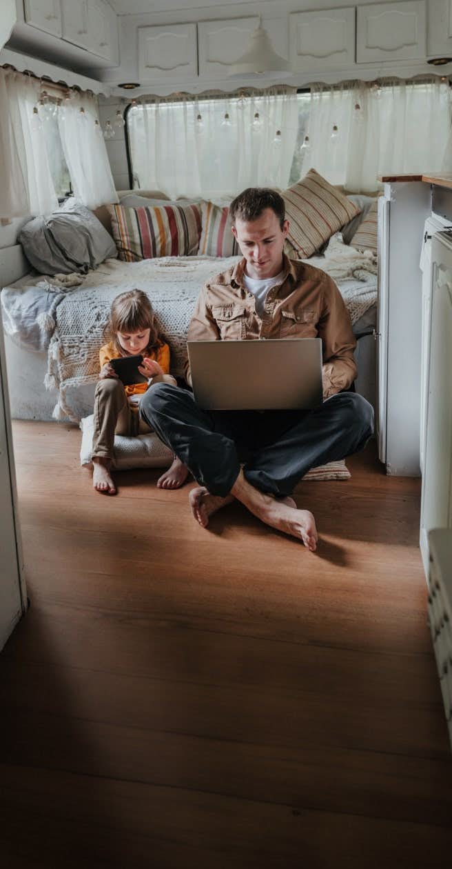 father and child using devices in rv