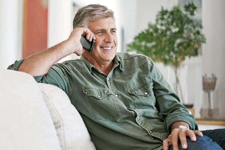 older man sitting on couch talking on cell phone
